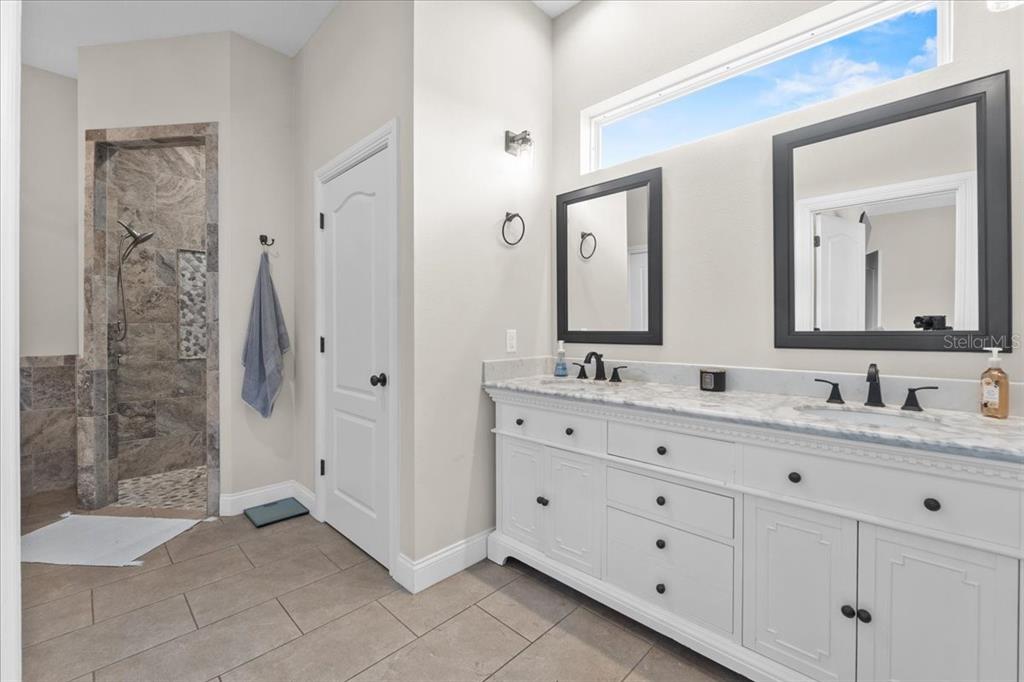11657 Moore Road Lakeland, FL 33809 - Photo 61 of 100 a bathroom with a double vanity sink a mirror and a shower