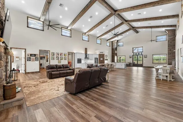 a large kitchen with stainless steel appliances kitchen island granite countertop a table chairs in it and a wooden floor