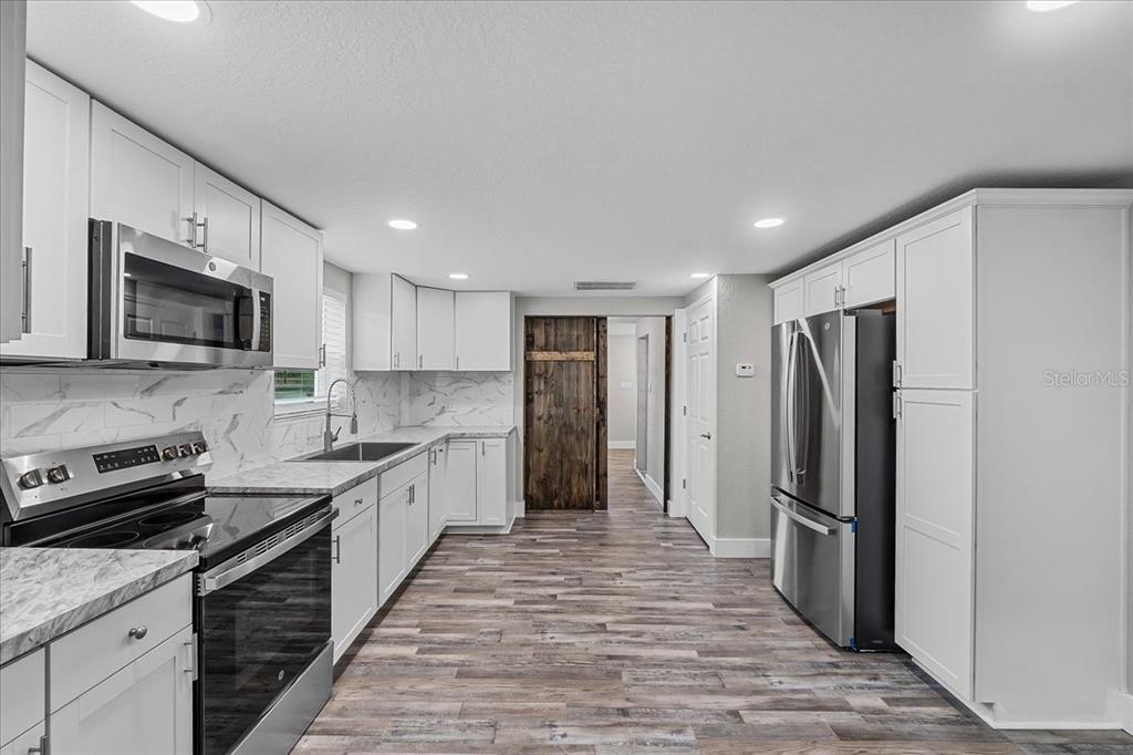 11657 Moore Road Lakeland, FL 33809 - Photo 88 of 100 a large kitchen with a refrigerator a sink a stove top oven and stainless steel appliances