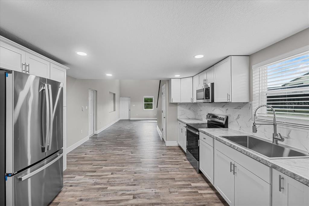 11657 Moore Road Lakeland, FL 33809 - Photo 89 of 100 a kitchen with stainless steel appliances granite countertop a refrigerator a sink dishwasher a stove top oven a refrigerator and white cabinets