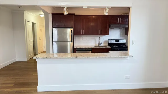 a kitchen with stainless steel appliances granite countertop a refrigerator a stove and a sink with wooden floor