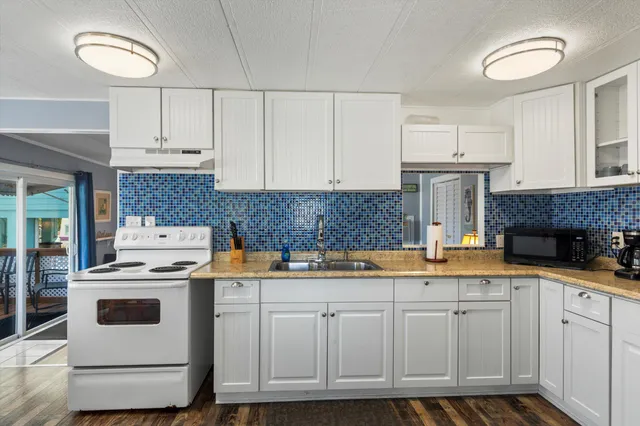 a kitchen with granite countertop a sink and white cabinets