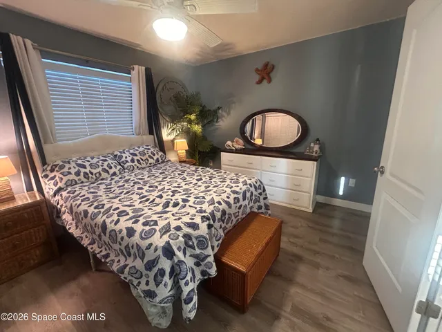 a bedroom with a bed and a chair with the wooden floor