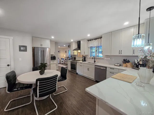 a open dining room with stainless steel appliances kitchen island granite countertop a dining table chairs and a refrigerator