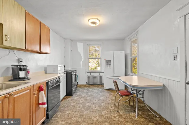 a kitchen with stainless steel appliances granite countertop a stove a sink dishwasher a microwave oven and a dining table with wooden cabinet