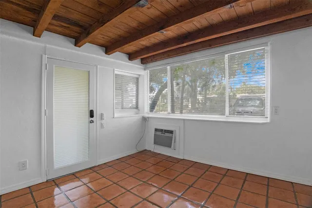 a view of an empty room with window and chandelier fan