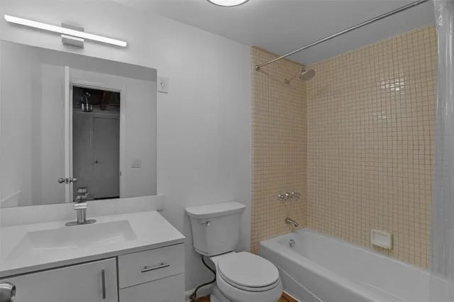 a bathroom with a bathtub shower sink vanity mirror and toilet