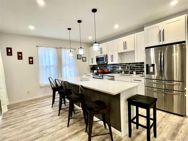 a kitchen with stainless steel appliances granite countertop a sink a stove a refrigerator and island with wooden floor