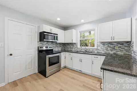 a kitchen with granite countertop a sink cabinets and stainless steel appliances