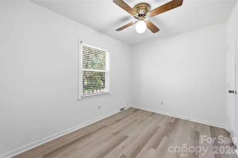an empty room with a window and ceiling fan