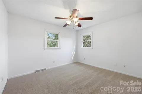 an empty room with windows and fan