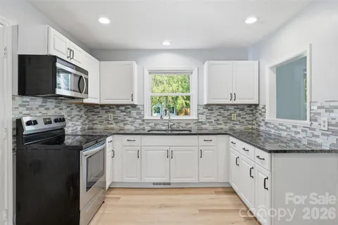 a kitchen with granite countertop white cabinets white stainless steel appliances with a sink and dishwasher