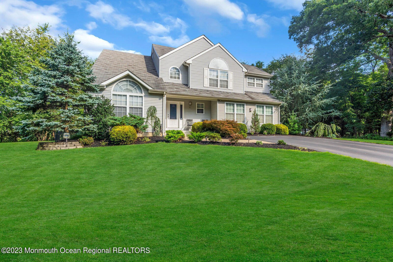 a front view of a house with a garden and trees
