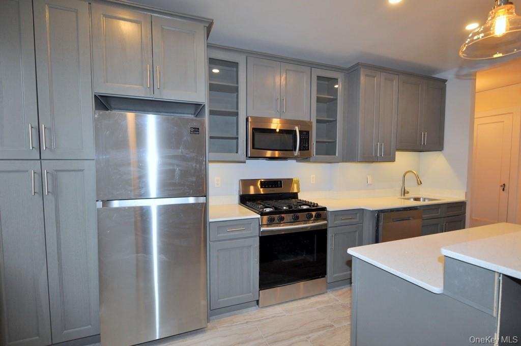 69 Harney Road, Unit 3A Scarsdale, NY 10583 - Photo 7 of 22 Renovated Kitchen with center Island, pendent lighting, Granite Counters, Stainless Steel Appliance including a dishwasher, range, microwave and refrigerator. The wall separating the eat-in-kitchen and living room have been removed and a center Island installed with electric and USB outlets installed to create an open concept.