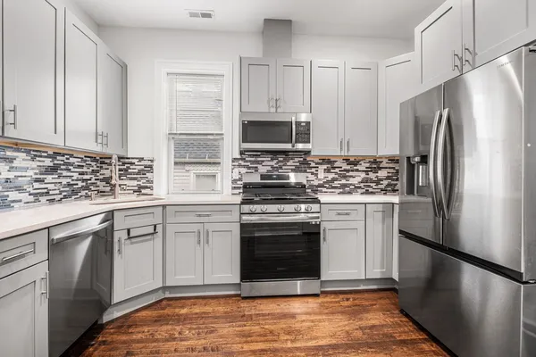 a kitchen with stainless steel appliances white cabinets and a stove top oven