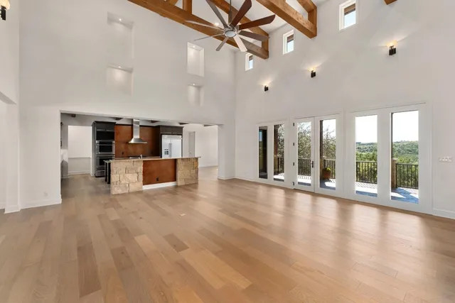 a view of an empty room with a window and kitchen view