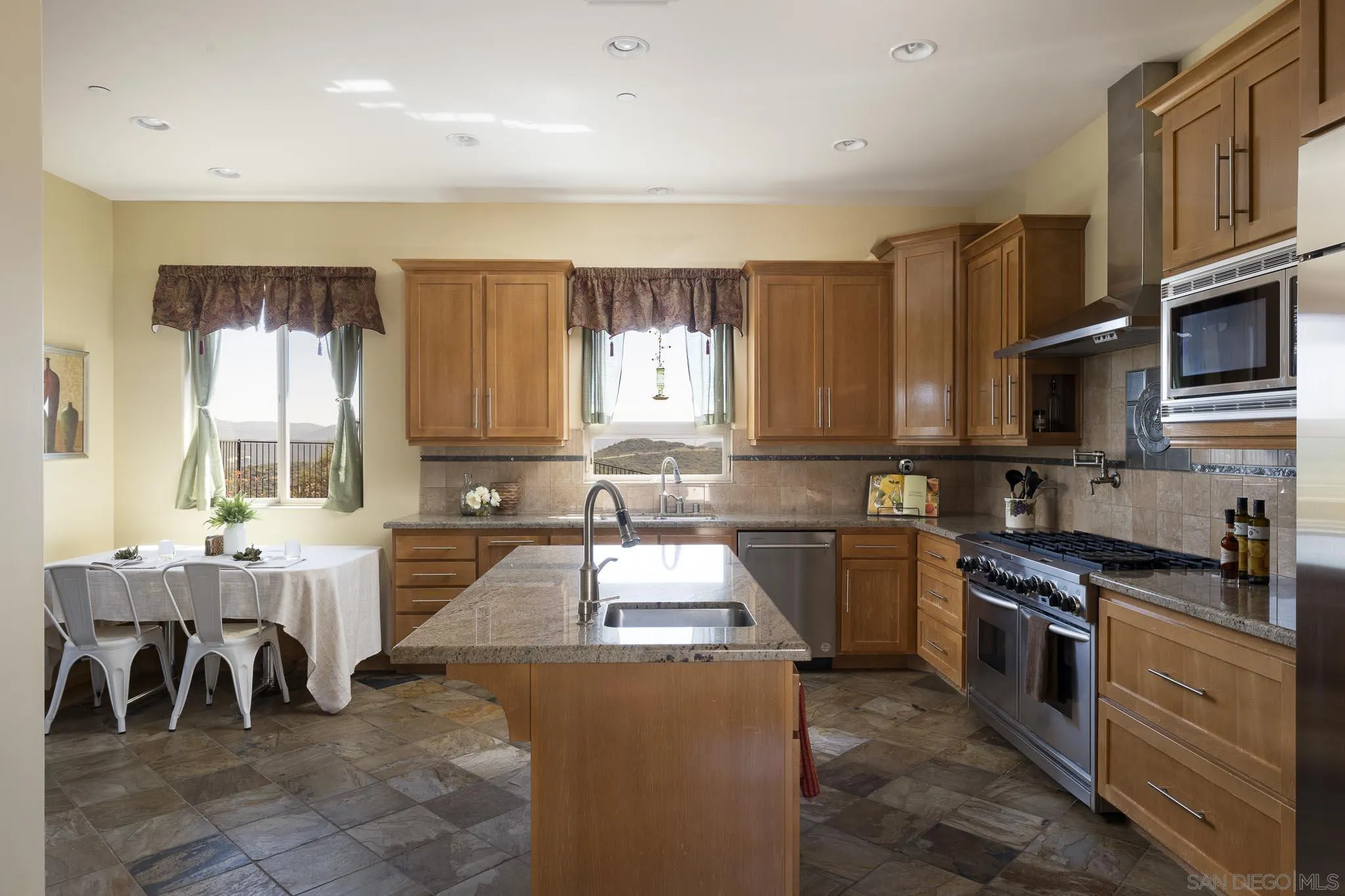 2001 Corte Sierra Alpine, CA 91901 - Photo 15 of 35 a kitchen with stainless steel appliances granite countertop a stove top oven a sink a dining table and chairs