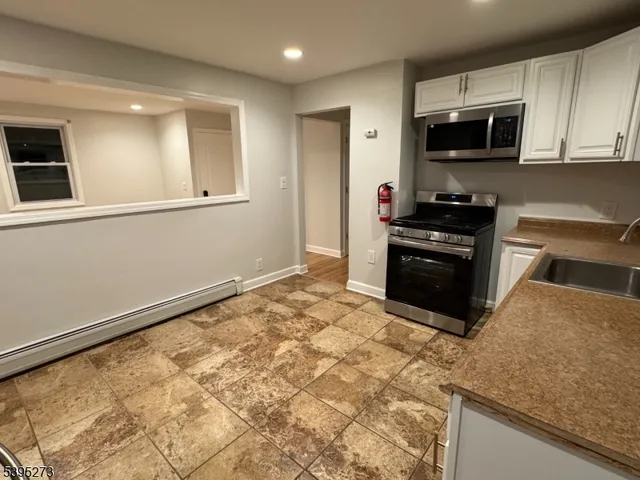 a kitchen with granite countertop a refrigerator and a stove top oven