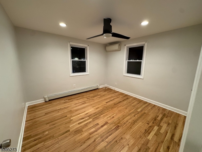 2 Woodside Avenue, Unit 1 Little Falls, NJ 07424 - Photo 5 of 13 an empty room with wooden floor ceiling fan and windows