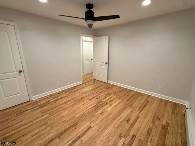 an empty room with wooden floor fan and windows
