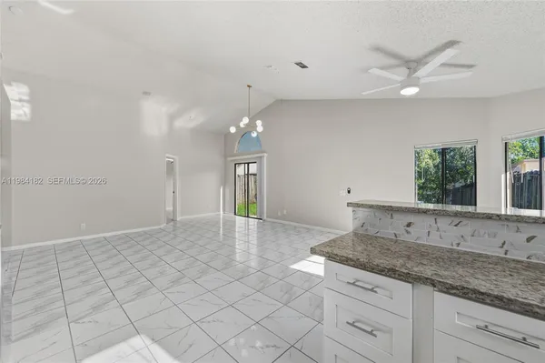 a kitchen with granite countertop a sink and white cabinets