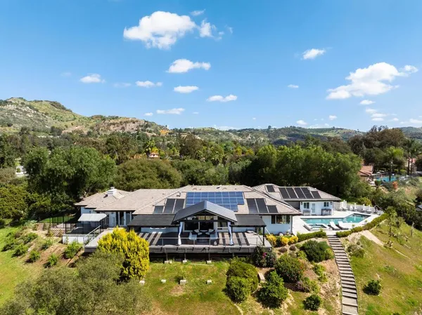 an aerial view of a house with swimming pool and mountains