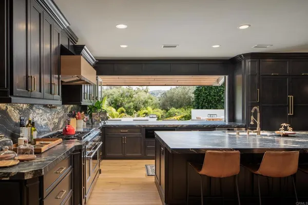 a kitchen with stainless steel appliances granite countertop a sink a stove and a wooden cabinets