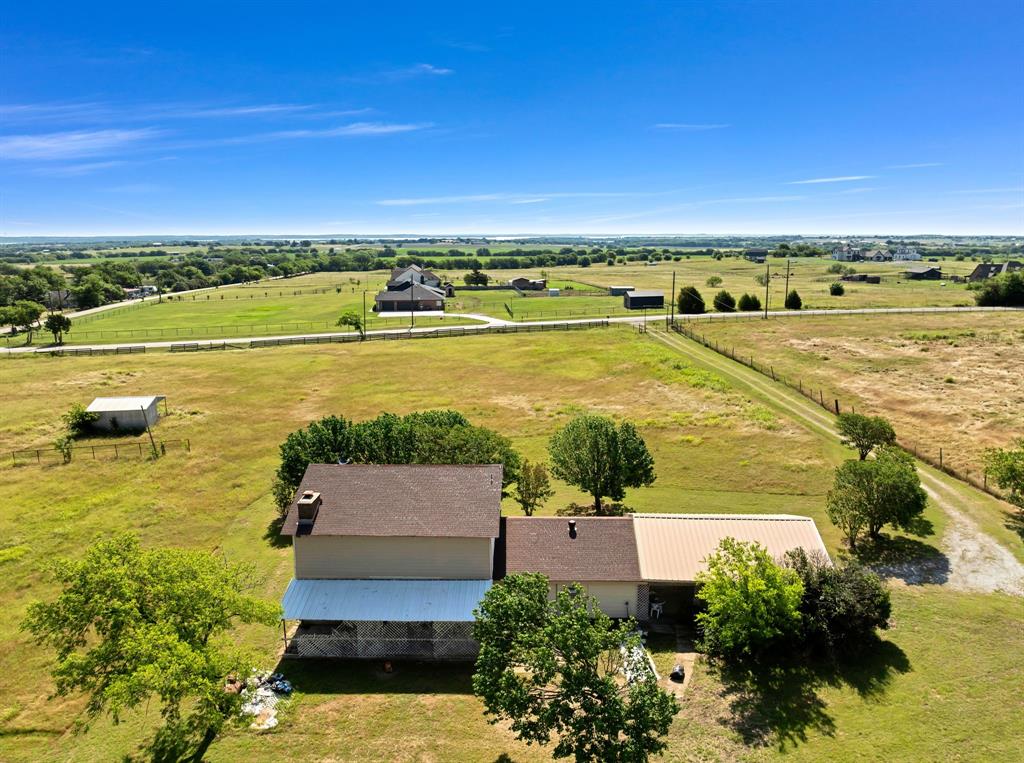 1795 Melton Road Sanger, TX 76266 - Photo 6 of 17 Expansive rural property featuring a two-story residence with a covered patio, an attached single-story structure with a metal roof, and a separate outbuilding
