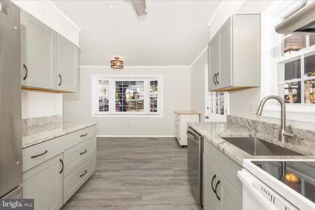 a kitchen with granite countertop white cabinets and window