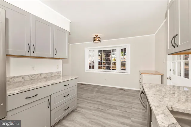 a kitchen with granite countertop white cabinets and window