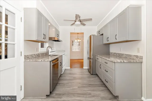 a kitchen with granite countertop a sink stove refrigerator and cabinets