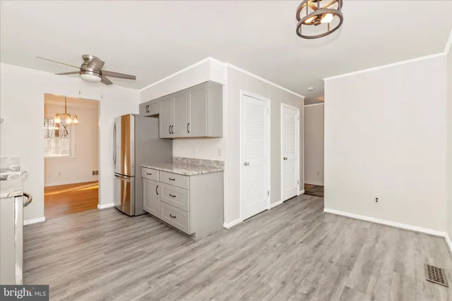 a kitchen with white cabinets and wooden floor