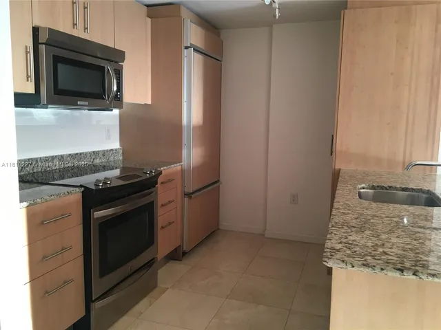 a kitchen with granite countertop cabinets stainless steel appliances and a counter space