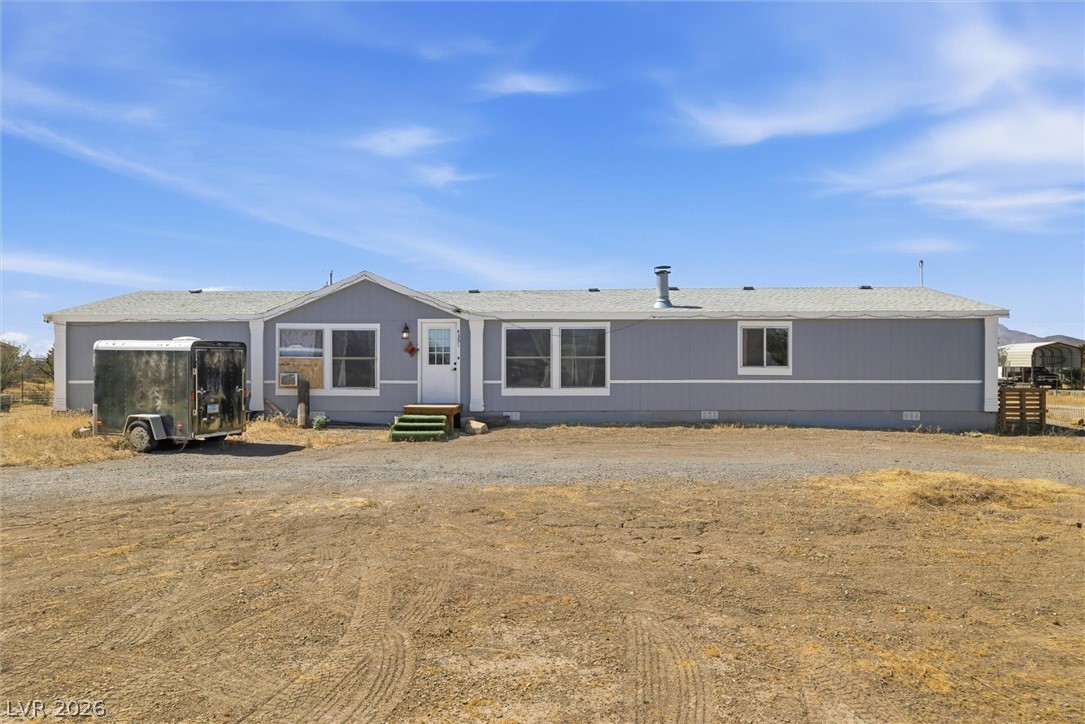 4331 Retread Road Pahrump, NV 89048 - Photo 2 of 31 A classic manufactured residence, this home presents a well-maintained facade against a wide-open landscape.