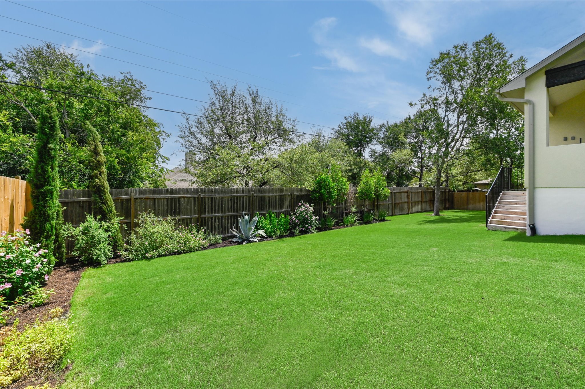 913 Presa Arriba Road Austin, TX 78733 - Photo 30 of 30 A spacious, verdant yard with mature landscaping and a well-maintained wooden fence.