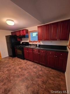 Kitchen with reddish brown cabinets, dark countertops, black appliances, and extractor fan