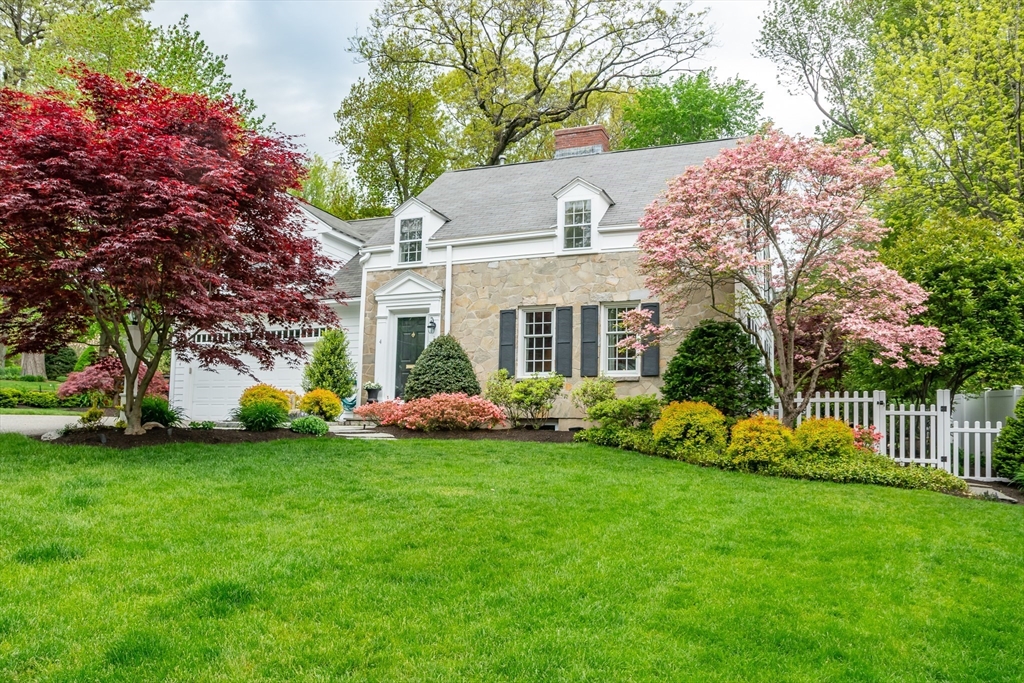 a front view of a house with a garden and trees