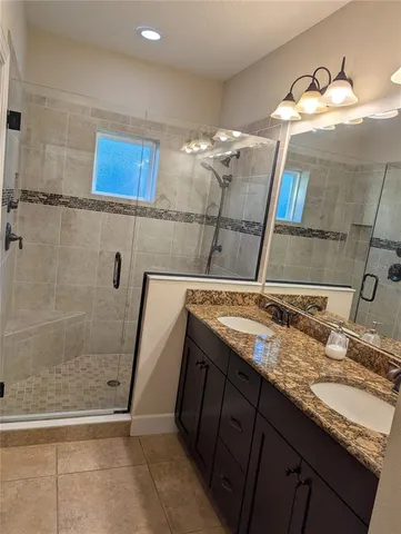 a bathroom with a granite countertop sink a mirror and shower