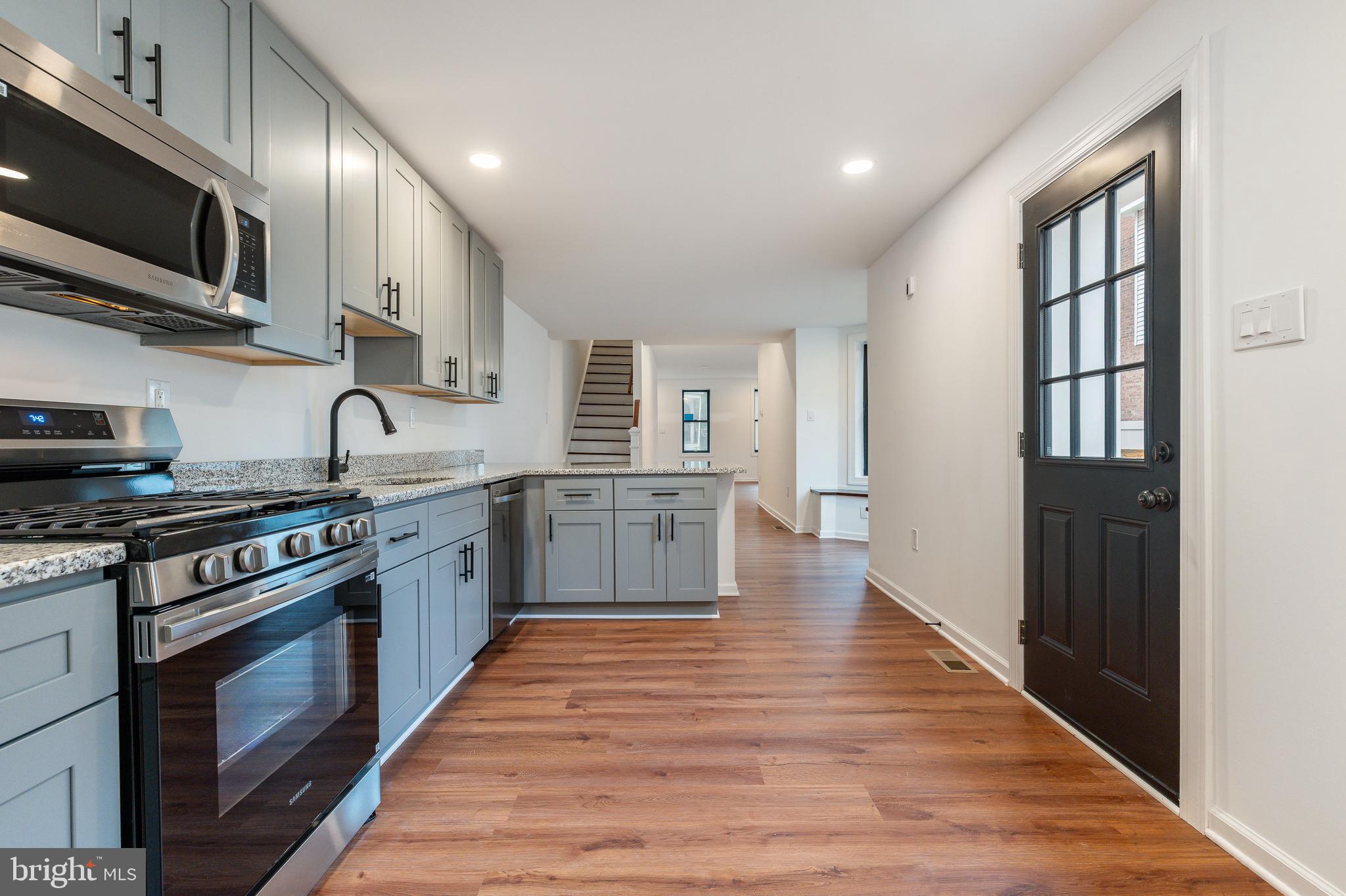 32 East Elm Street Norristown, PA 19401 - Photo 7 of 65 a kitchen with stainless steel appliances granite countertop a stove top oven a sink dishwasher and a microwave oven with wooden floor