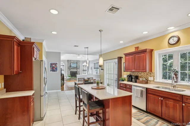 a kitchen with stainless steel appliances kitchen island granite countertop a refrigerator a sink a stove a dining table and chairs