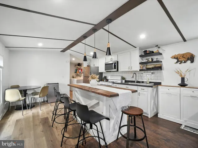 a kitchen with stainless steel appliances granite countertop a dining table chairs refrigerator and sink