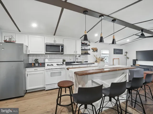 a kitchen with stainless steel appliances granite countertop a dining table chairs refrigerator and microwave