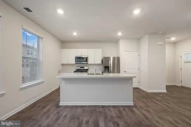 a view of kitchen with stainless steel appliances granite countertop a stove top oven a refrigerator a sink and dishwasher with wooden floor
