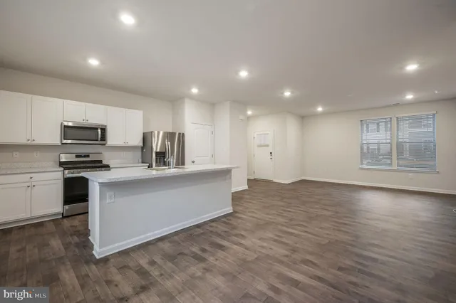 a large white kitchen with kitchen island a sink dishwasher a stove and a refrigerator with wooden floor