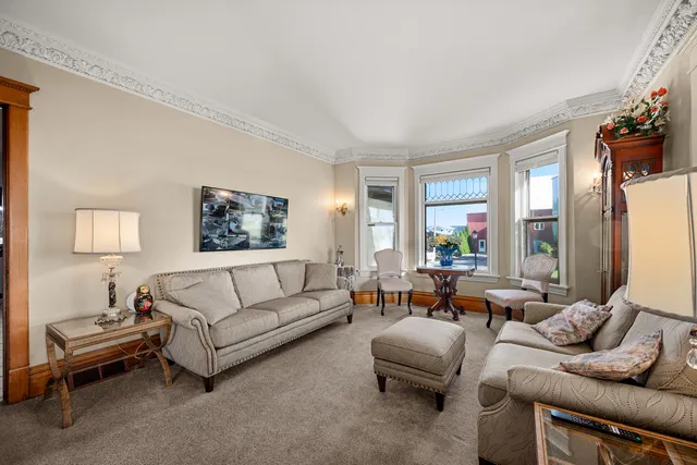 a living room with furniture a rug a fireplace and a large window
