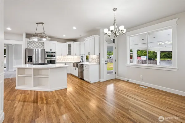 a view of a kitchen with kitchen island wooden floor and stainless steel appliances