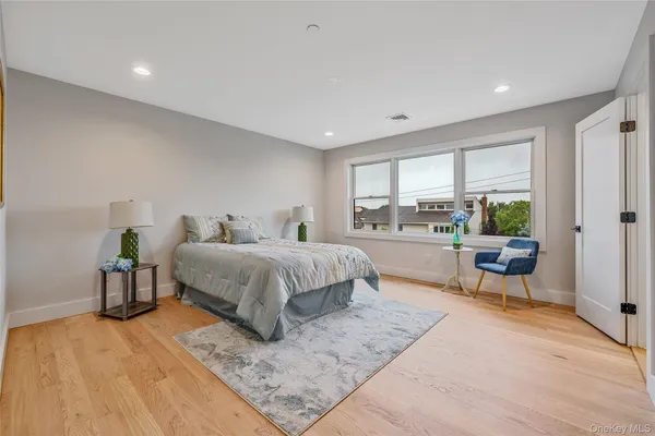 a spacious bedroom with a bed a table and three large window