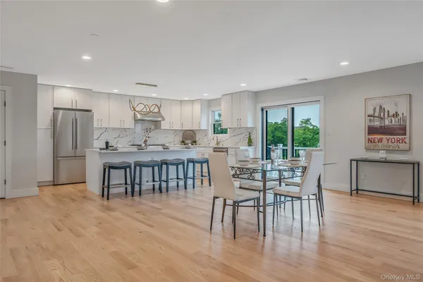 a kitchen with stainless steel appliances granite countertop a dining table chairs refrigerator and sink