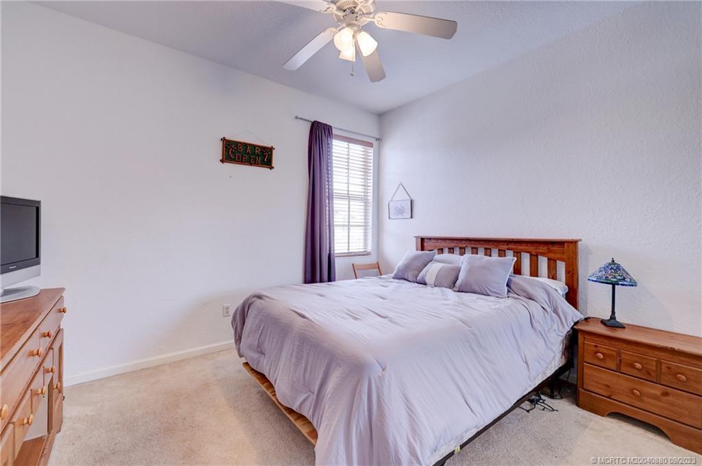 316 Southwest Otter Run Place Stuart, FL 34997 - Photo 27 of 50 a spacious bedroom with a bed and a chandelier