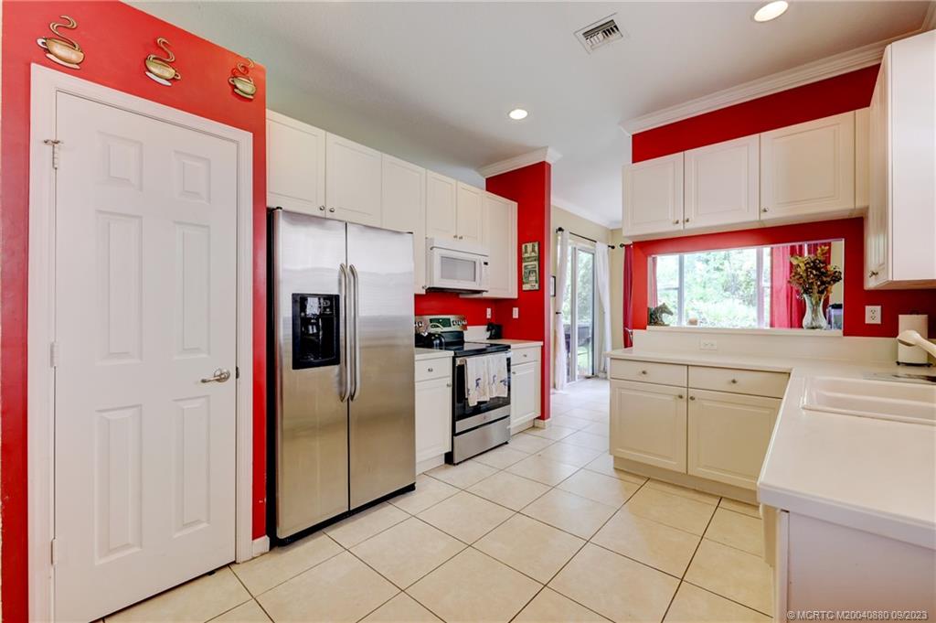 316 Southwest Otter Run Place Stuart, FL 34997 - Photo 8 of 50 a kitchen with stainless steel appliances kitchen island granite countertop a refrigerator and a stove top oven